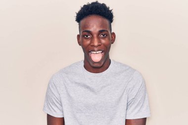Genç, Afro-Amerikan bir adam günlük kıyafetler giyiyor. Dilini komik bir ifadeyle dışarı çıkarıyor. duygu kavramı. 