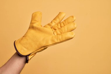 Avuç içi açık, destek ve yardım için uzanan, yardım jesti sunan, izole edilmiş sarı arka plan üzerinde bahçıvan eldiveni ile beyaz bir gencin eli.
