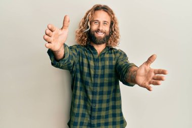 Sakallı, uzun saçlı, sıradan kıyafetler giyen yakışıklı bir adam kameraya sarılıp gülümsüyor. Mutluluğu kucaklayan neşeli bir ifade.. 