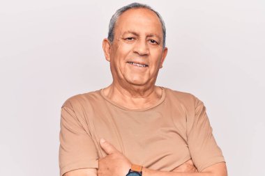 Gri saçlı, sıradan tişörtlü, mutlu yüzlü, kollarını kavuşturup kameraya bakan son sınıf öğrencisi. pozitif kişi. 