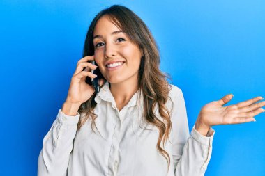 Genç esmer kadın akıllı telefondan konuşuyor gülümsüyor elleri ve parmakları gülen yüzüyle çerçeve yapıyor. yaratıcılık ve fotoğrafçılık kavramı. 
