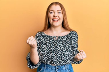 Çiçek desenli gömlek giyen genç ve güzel bir kadın kolları havada ve gözleri kapalı bir şekilde başarıyı kutluyor. 