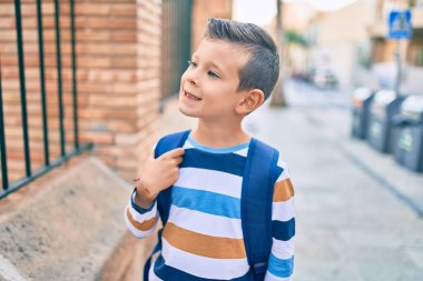 Sevimli beyaz bir öğrenci şehirde mutlu bir şekilde gülümsüyor..