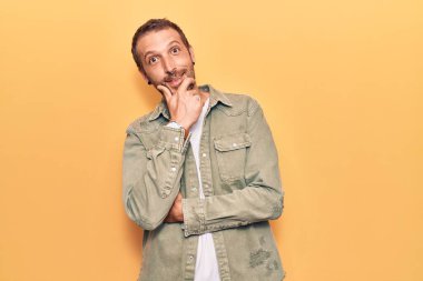 Sıradan kıyafetler giyen, kameraya kendinden emin, kolları çapraz ve çenesi havada gülümseyen genç yakışıklı bir adam. Olumlu düşünmek. 