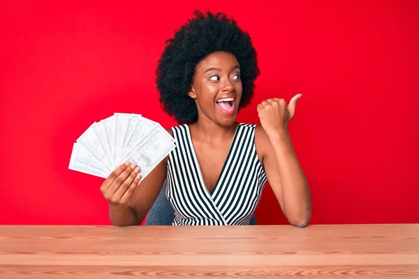 Jovem Afro Americana Segurando Dólares Apontando Polegar Para Lado Sorrindo — Fotografia de Stock