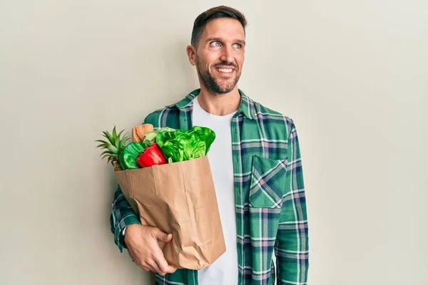 Hombre Guapo Con Barba Sosteniendo Bolsa Papel Con Comestibles Sonriendo —  Fotos de Stock