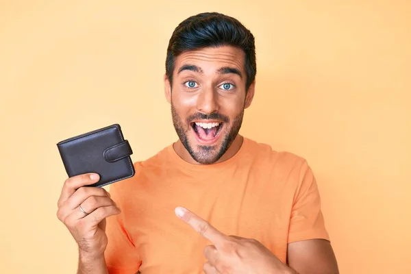 Joven Hombre Hispano Sosteniendo Cartera Cuero Sonriendo Feliz Señalando Con —  Fotos de Stock