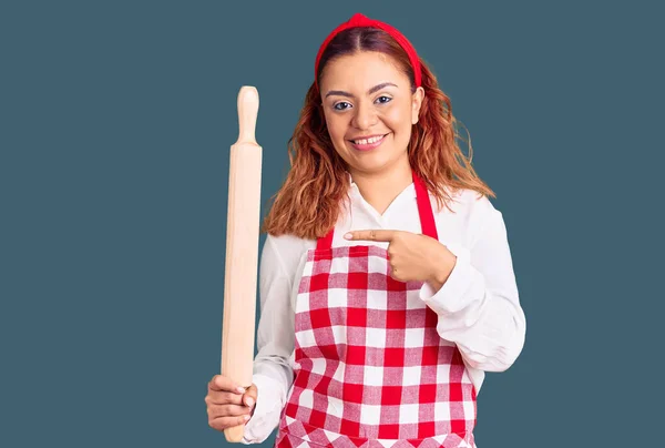 Mujer Latina Joven Usando Delantal Sosteniendo Amasadora Sonriendo Feliz Señalando —  Fotos de Stock