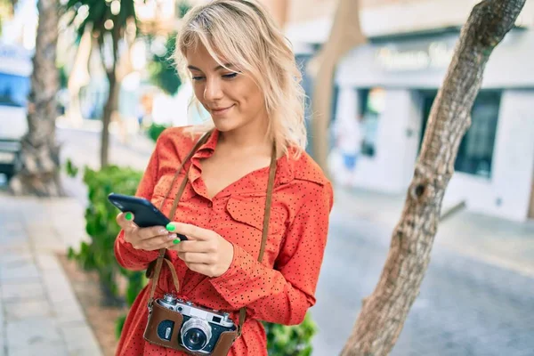 若いですブロンド女性笑顔幸せな使用スマートフォンで市 — ストック写真