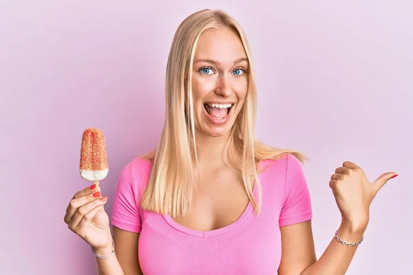 Jovem Loira Segurando Sorvete Apontando Polegar Até Lado Sorrindo Feliz — Fotografia de Stock