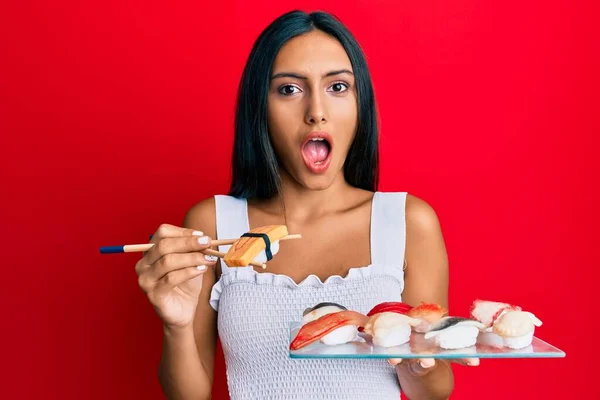 若いブルネットの女性は箸を使用してオムレツ寿司を食べて恐れて 驚きと驚きの表情でショックを受けました 恐怖と興奮した顔 — ストック写真