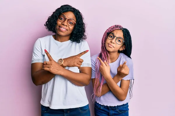 美丽的非洲裔美国母亲和女儿穿着休闲装 戴着眼镜 手指指向两边 方向不同 意见不一 — 图库照片