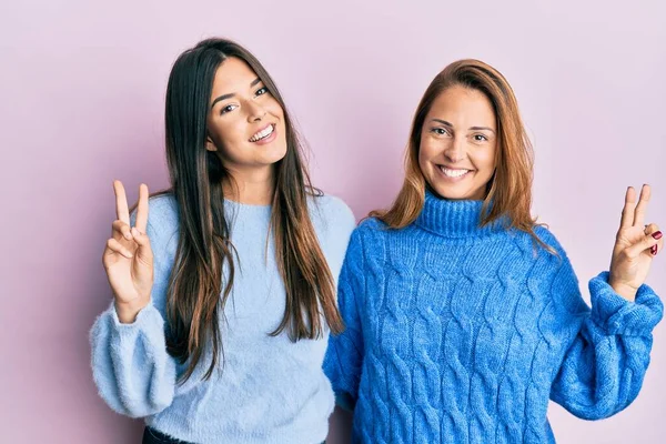 西班牙裔家庭的母亲和女儿穿着羊毛衫 笑着看着摄像机 手指头在做胜利的标志 第二点 — 图库照片