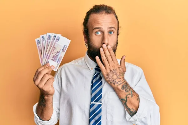 髭と長い髪を持つハンサムなビジネスマンは 手で口をカバーロシアの500ルーブル紙幣を保持し ショックを受け 間違いを恐れています 驚きの表情 — ストック写真