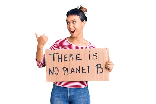 Young Woman Holding Planet Banner Pointing Thumb Side Smiling Happy — Stock Photo, Image