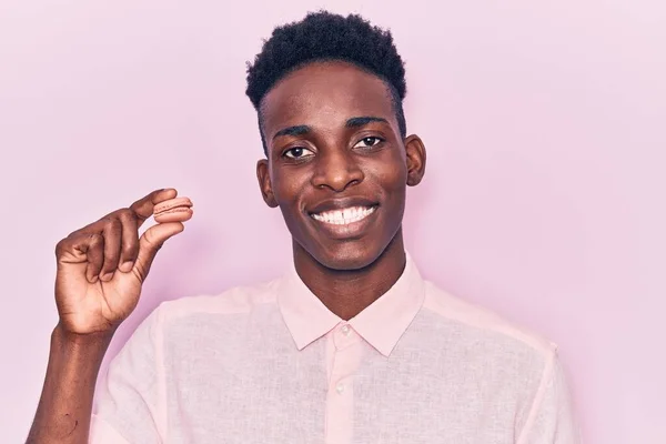 Mladý Africký Američan Drží Macaron Vypadá Pozitivně Šťastně Stojící Usmívá — Stock fotografie