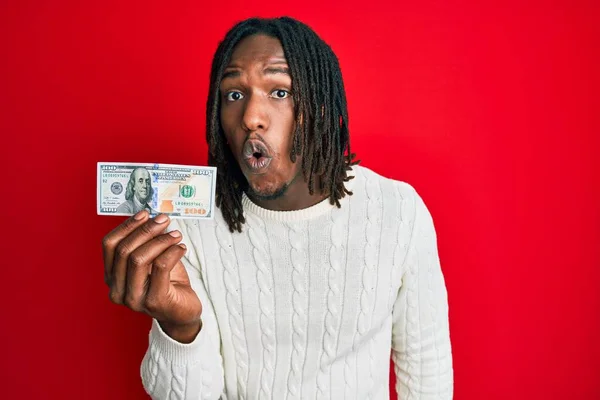 100ドルの紙幣を保持しているアフリカ系アメリカ人の男は怖がって 驚きのために口を開けて驚いて 不信の顔 — ストック写真