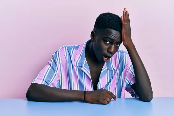 Νεαρός Αφροαμερικάνος Που Φοράει Καθημερινά Ρούχα Κάθεται Στο Τραπέζι Έκπληκτος — Φωτογραφία Αρχείου