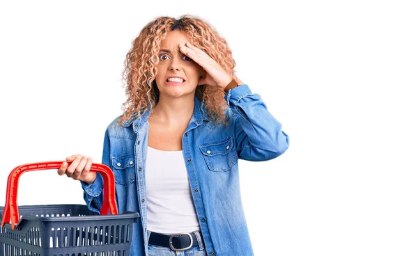 Young Blonde Woman Curly Hair Holding Supermarket Shopping Basket Stressed — Stock Photo, Image