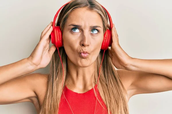 Mujer Rubia Joven Escuchando Música Usando Auriculares Haciendo Cara Pez — Foto de Stock