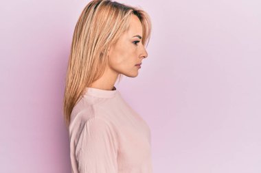 Kış süveteri giyen güzel sarışın kadın yan yan yan bakıyor, rahat poz veriyor kendine güveni olan doğal bir yüz takınıyor.. 