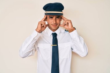 Genç İspanyol adam uçak pilotu üniforması giyiyor. Yüksek sesli müzik sesi için kulaklarını parmaklarıyla kapatıyor. sağır kavramı. 