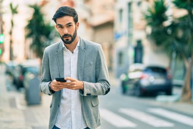Şehirde akıllı telefon kullanan Latin asıllı genç bir işadamı..