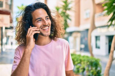 Genç İspanyol adam gülümsüyor. Şehirdeki akıllı telefondan konuşuyor..