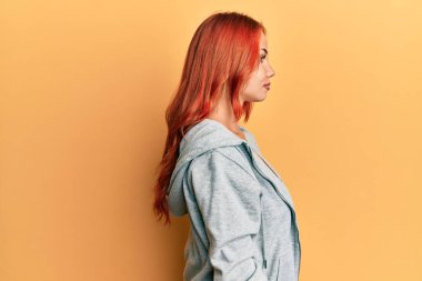 Genç, güzel, kızıl saçlı, sıradan, sportif bir kazak giyen rahat bir profil pozu veren, kendine güvenen bir gülümsemesi olan bir kadın.. 