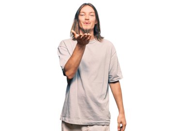 Uzun saçlı yakışıklı beyaz adam, sıradan kıyafetler giyiyor kameraya bakıyor ve havada bir öpücük savuruyor. Güzel ve seksi. aşk ifadesi. 