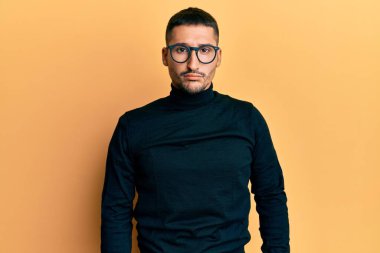 Balıkçı yaka kazak ve gözlük takan yakışıklı bir adam depresif ve endişeli, sinirli ve korkmuş. hüzünlü ifade. 