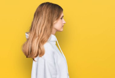 Güzelim beyaz kız, günlük kazak giyiyor, rahat bir görünüm takınıyor, doğal bir yüz ifadesi ve kendine güvenen bir gülüşü var.. 