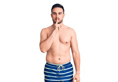 Mayo giyen genç ve yakışıklı bir adam parmakları dudaklarında sessiz olmak istiyor. sessizlik ve gizli konsept. 