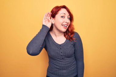 Sarı arka planda dikilen sıradan bir kazak giyen genç, güzel, kızıl saçlı bir kadın. Kulağı kulağında, dedikoduları ve dedikoduları dinliyor. Sağırlık kavramı.