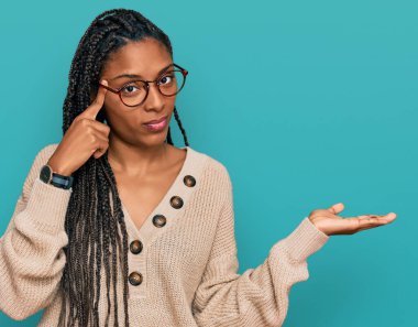 Sıradan kıyafetler giyen Afro-Amerikalı bir kadın avuç içinin açık olmasından rahatsız ve kafası karışmış bir şekilde fotokopi alanını gösteriyor ve alnını işaret ediyor. Bunu bir düşün.. 