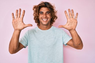 Gündelik kıyafetler giyen genç İspanyol adam on numarayı gösterip işaret ederken kendinden emin ve mutlu bir şekilde gülümsüyor.. 