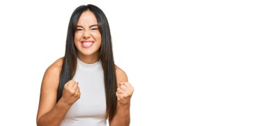 Gündelik giysiler giyen genç, güzel İspanyol kız. Başarı için heyecanlanan, kollarını kaldıran ve gözleri kapalı zaferi kutlayan kız. Kazanan konsept. 