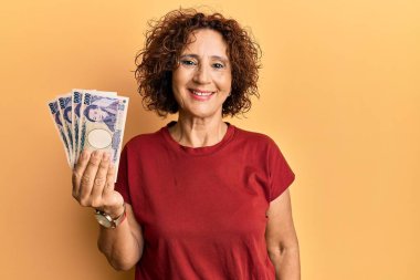 Güzel, orta yaşlı, olgun bir kadın elinde 5000 Japon doları tutuyor. Pozitif ve mutlu görünüyor. Kendine güvenen bir gülümsemeyle dişlerini gösteriyor. 