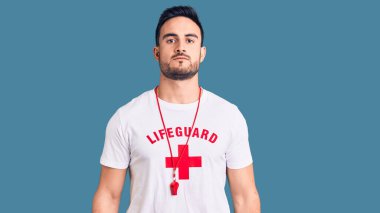 Cankurtaran üniforması giyen genç yakışıklı adam yüzünde ciddi bir ifadeyle rahatlamış. Basit ve doğal bir şekilde kameraya bakıyorsun.. 