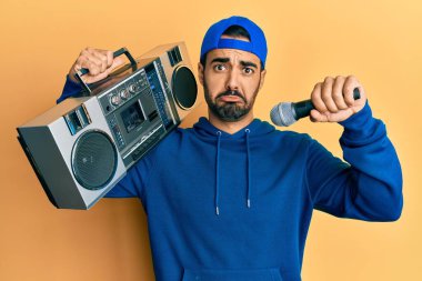 Kasetçalar tutan genç İspanyol adam, mikrofonla şarkı dinlerken bunalımlı ve üzüntülü, sinirli ve korkmuş bir şekilde ağlıyor. hüzünlü ifade. 