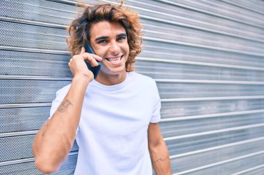 Genç İspanyol adam şehrin caddesinde akıllı telefondan konuşuyor.