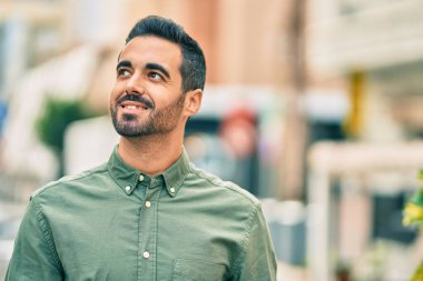 Genç İspanyol adam gülümseyerek şehirde mutlu mesut dikiliyor..