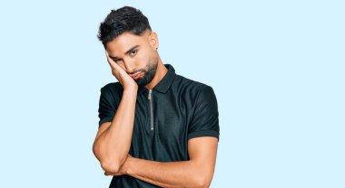 Spor kıyafetleri giyen genç adam kollarını kavuşturarak depresyondan yorgun ve sıkılmış göründüğünü düşünüyor.. 