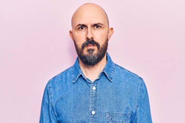 Gündelik kıyafetler giyen genç yakışıklı adam yüzünde ciddi bir ifadeyle rahatlamış. Basit ve doğal bir şekilde kameraya bakıyorsun.. 