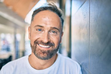 Orta yaşlı, yakışıklı, gülümseyen, mutlu, şehrin duvarına yaslanmış bir adam..