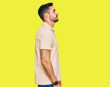 Latin kökenli genç adam rahat bir görünüm takınıyor, rahat bir görünüm takınıyor, kendine güvenen bir gülümsemeyle.. 