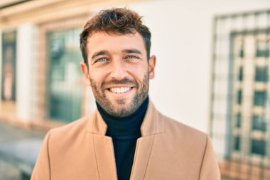 Zarif ceket giyen yakışıklı iş adamı dışarıda mutlu bir şekilde gülümsüyor.