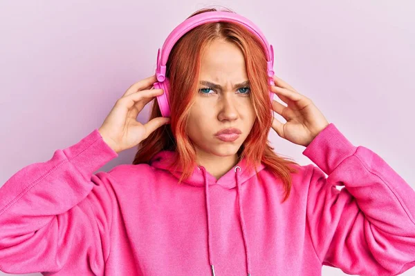 Mujer Pelirroja Joven Escuchando Música Usando Auriculares Escépticos Nerviosos Frunciendo — Foto de Stock