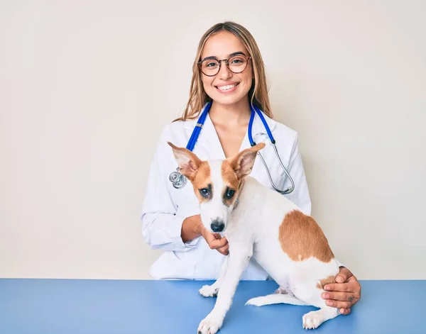 Молодая Красивая Блондинка Ветеринар Женщина Проверяет Здоровье Собаки Улыбаясь Счастливой — стоковое фото
