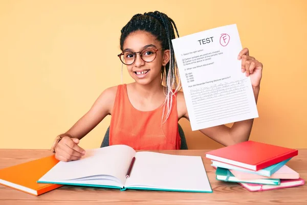 Young african american girl child with braids showing failed exam looking positive and happy standing and smiling with a confident smile showing teeth